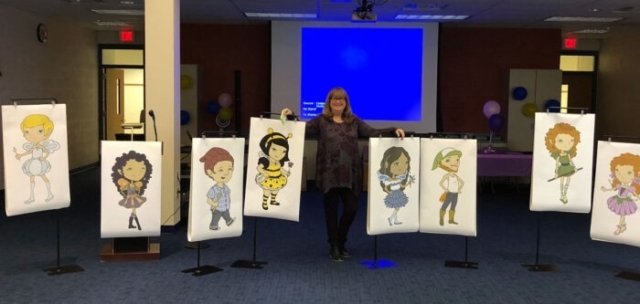 Mary posing between easels holding posters of all of her characters